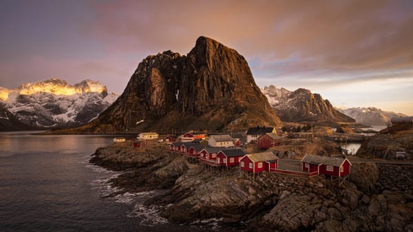 Red Fishermans huts (Rorbuer in Norwegian) in front of a majestic mountain in Norway's Lofoten Islands